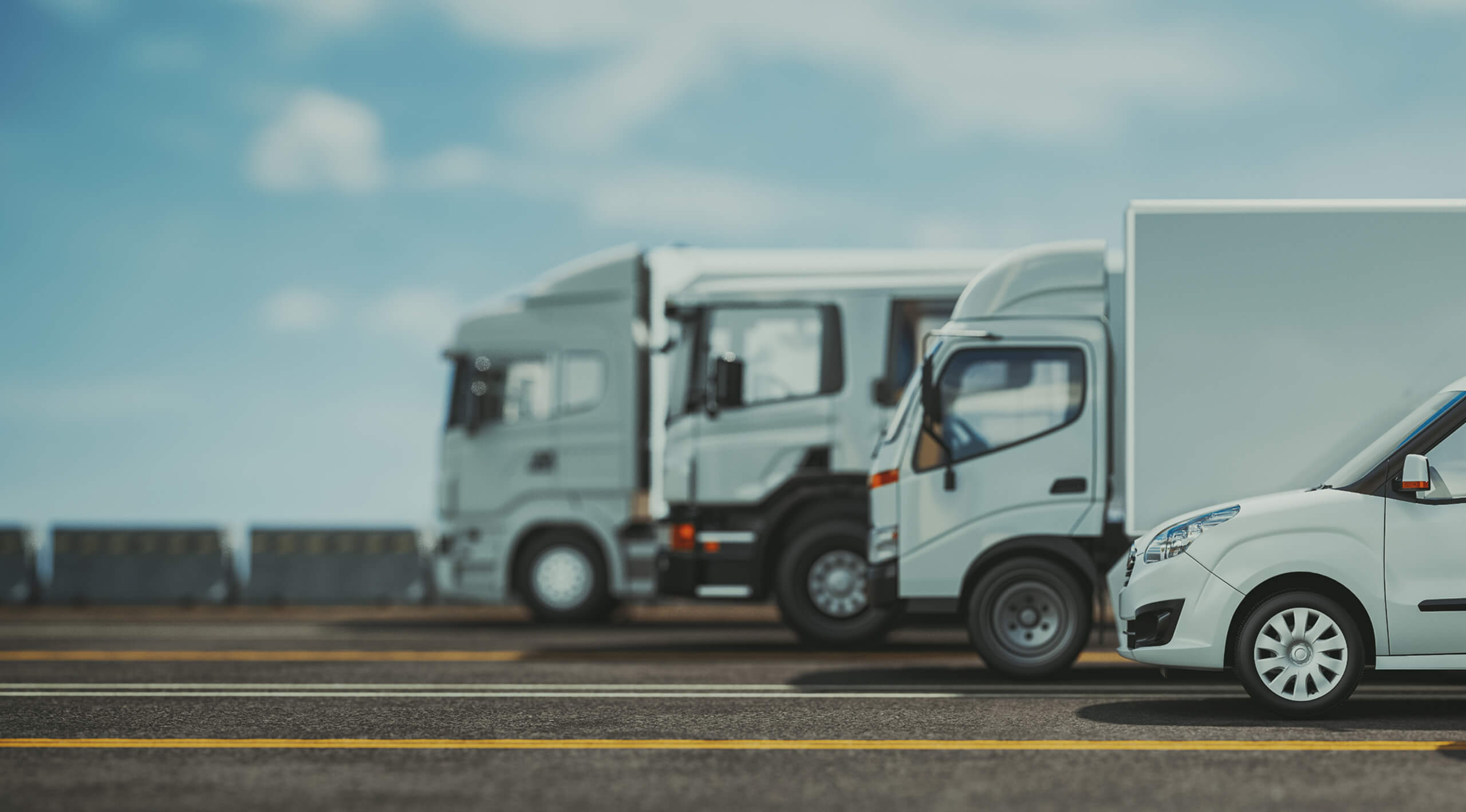 A row of white trucks parked neatly in a spacious parking lot under clear blue skies.